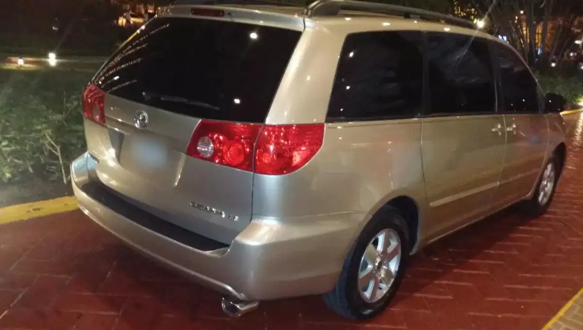Toyota Sienna dorada vista por detrás, de noche, sobre un parqueo de adoquines rojos
