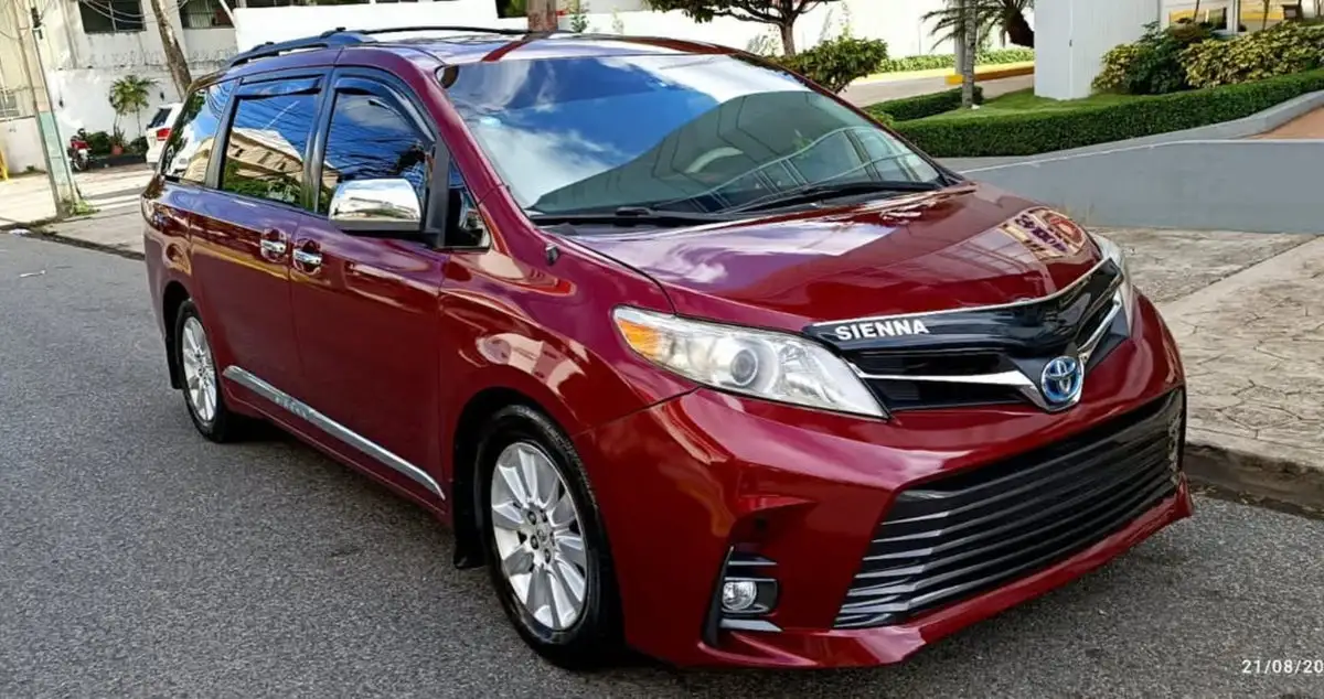 Toyota Sienna roja vista de tres cuartos, estacionada en una calle residencial con palmeras