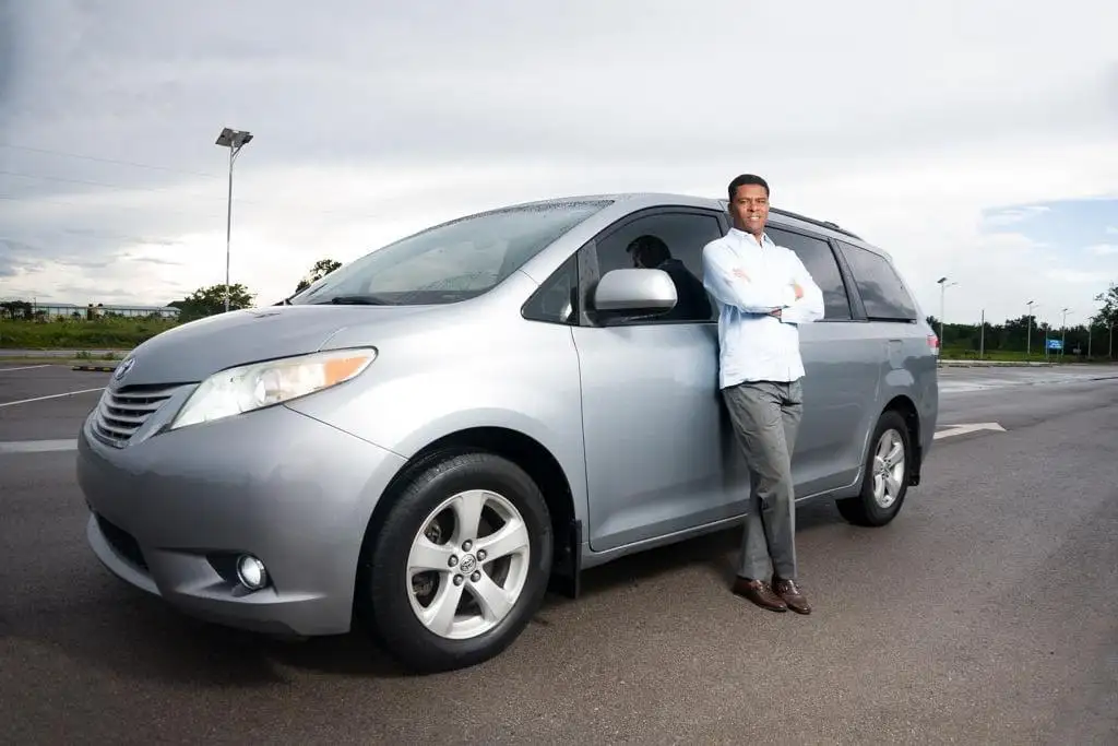 Julián Figuereo de pie junto a una Toyota Sienna de la flota