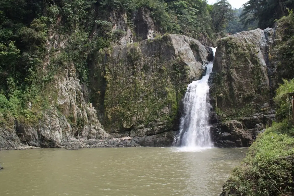 El Salto de Jimenoa cayendo entre paredes de roca con vegetación a una poza