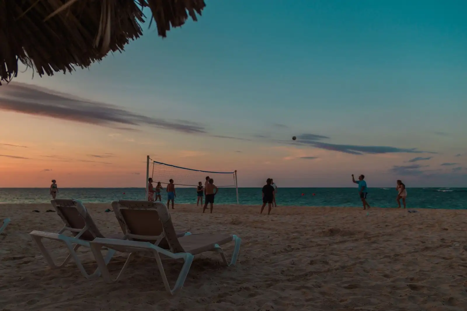 Voleibol de playa al atardecer en Punta Cana, con palapa y sillas de playa