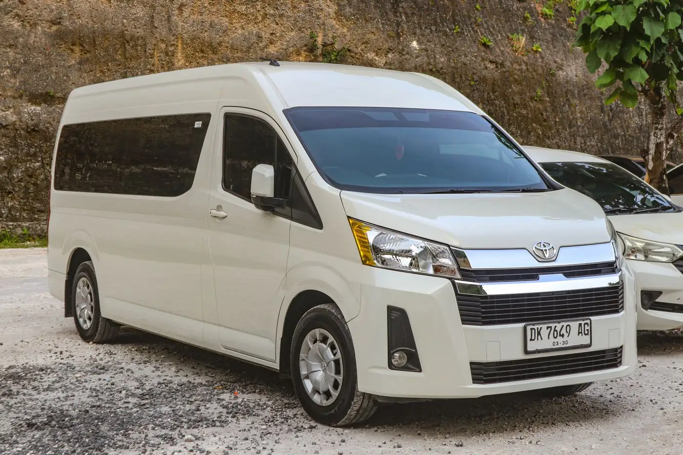 Una Toyota HiAce blanca de techo alto, vista de frente y de lado