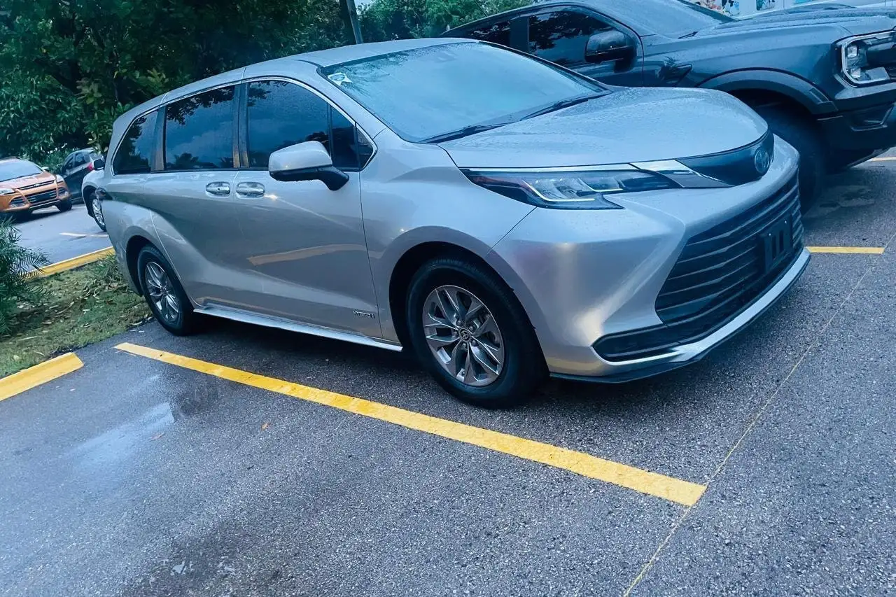 Toyota Sienna Hybrid plateada de Julián Transporte estacionada, vista de lado en tres cuartos